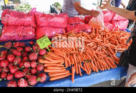 Frau, die frisches Bio-Gemüse, Karotten und Radieschen auf dem Dorfbasarmarkt in Manavgat, Antalya, Türkei, kauft. Stockfoto