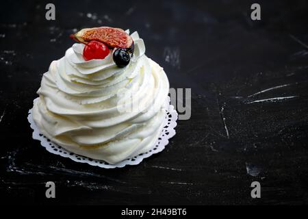 Schlagsahne auf schwarzem Hintergrund mit Platz für Text. Baiser-Dessert mit Beeren aus der Nähe. Ein schönes Dessert mit Baiser, Beeren und c Stockfoto