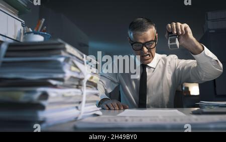 Ärgerter frustrierter Büroangestellter, der in seinem Büro wiederholt gearbeitet hat Stockfoto