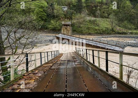 Eine Brücke über einen Gebirgsfluss, der vom Wasser zerstört wurde. Stockfoto