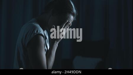 Traurige Frau wacht spät in der Nacht auf, sie leidet an Schlaflosigkeit Stockfoto