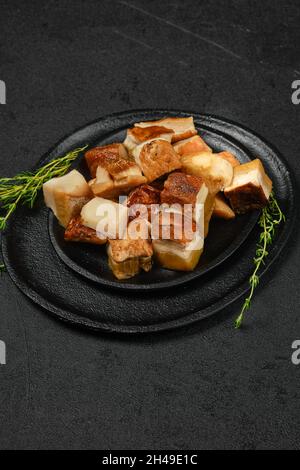 Gefrorener frischer Boletus auf Stücken auf schwarzem Steinteller geschnitten Stockfoto