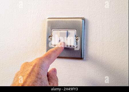 Nahaufnahme eines männlichen Fingers, der zu Hause einen Lichtschalter ein- oder ausschaltet. Strom, Energie, Elektrik Sparen. Speicherplatz kopieren. Stockfoto