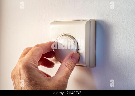 Einstellung der Temperatur von Hand an einem wandmontierten Thermostat. Zentralheizung. Stockfoto