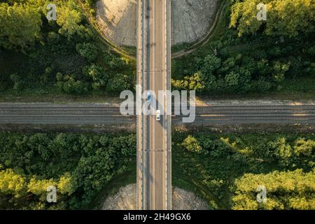 Luftaufnahme von oben nach unten über den Autobahnviadukt mit der Eisenbahn. Drohnenansicht der Brücke mit Autos über die Eisenbahn. Überquerung der Eisenbahnlinie und der Autobahn Stockfoto