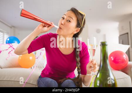 Glückliche asiatische Frau Raising Party Trompete und Champagner Glas machen Silvester Laptop-Videoanruf Stockfoto