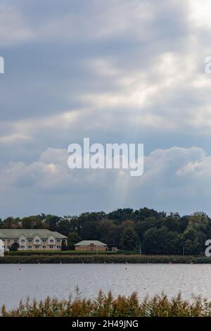 Die Sonne strahlt durch Wolken über einem glänzenden großen See Stockfoto