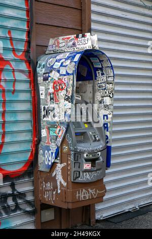 Ein Geldautomat, der mit Graffiti, Tags und Aufklebern bedeckt ist. Auf der Grand Street in Williamsburg, Brooklyn, New York City. Stockfoto