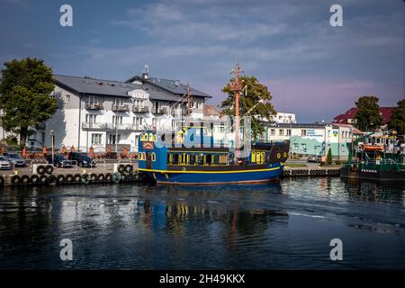 Dziwnow, Polen - 10. September 2021: Ein blaues und gelbes Touristenboot liegt am Pier vor. Stockfoto