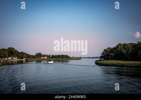 Dziwnow, Polen - 10. September 2021: Ein kleines Motorboot auf dem Fluss Dziwna, in der Nähe des Hafeneingangs. Stockfoto