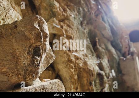 Primitive religiöse Skulptur, die ein Gesicht mit Wut oder Angstausdruck in der Troglodytenkirche der Saint Antoine Hermitage, Frankreich darstellt Stockfoto