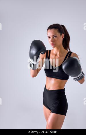 Junge attraktive europäische Fitness-Frau mit Boxhandschuhen posiert in trotzigen und wettbewerbsfähigen Kampf Haltung, Kämpfer Konzept isoliert im Studio backgr Stockfoto