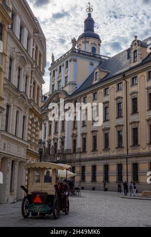 Breslau, Polen - 7. August 2021: Ein Hansom-Taxi wartet auf Touristen auf dem Universitätsplatz in der Altstadt von Breslau. Historische Gebäude im Hintergrund. Stockfoto