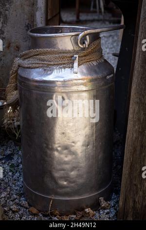 Ein alter Milchbehälter aus Metall, der auf dem Boden steht. Stockfoto