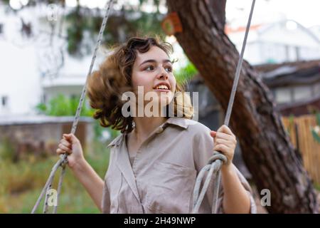 Schönes junges Mädchen auf Schaukel. Offene Momente Stockfoto