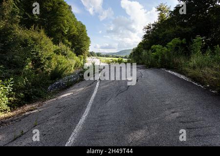 Geschwollener Asphalt. Die zerstörten Folgen der Straße des natürlichen Kataklysmus des Erdrutsches des Bodens. Asphalt durch Erdrutsch verschoben. Stockfoto