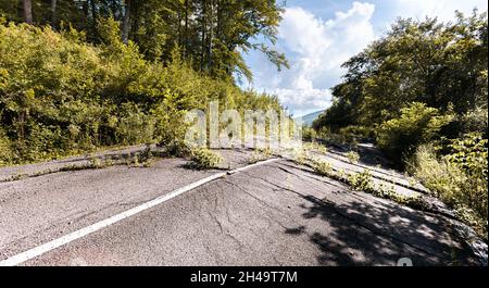 Geschwollener Asphalt. Die zerstörten Folgen der Straße des natürlichen Kataklysmus des Erdrutsches des Bodens. Asphalt durch Erdrutsch verschoben. Stockfoto