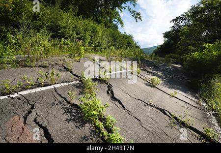 Geschwollener Asphalt. Die zerstörten Folgen der Straße des natürlichen Kataklysmus des Erdrutsches des Bodens. Asphalt durch Erdrutsch verschoben. Stockfoto