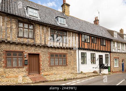 Alte Feuerstein- und Fachwerkhäuser, mit Steg verbunden, im Dorf Little Walsingham, Norfolk, Großbritannien. Stockfoto