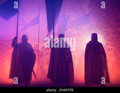 Kreuzritter in Kolonne, die in der Nacht in einem Wald vorrücken. Mittelalter, Waffen und Schwerter. Kriege. Templer. Banner winken. 3d-Rendering Stockfoto