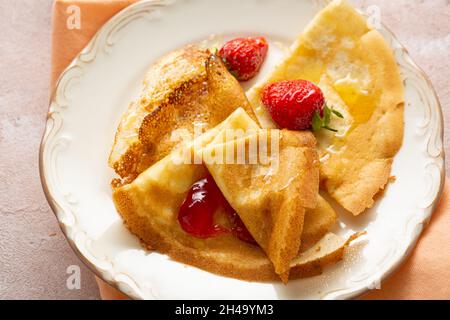 Nahaufnahme von Crepes mit Erdbeermarmelade auf dem Frühstücksteller Stockfoto