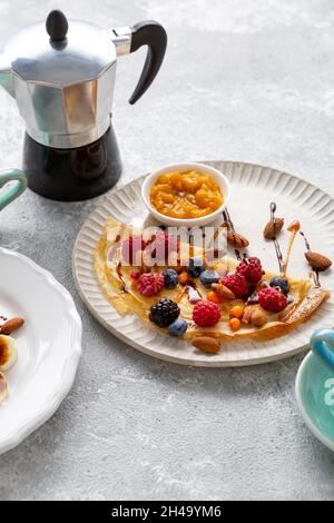 Frühstück Crepes mit Beeren und Marmelade Kaffeetassen Kanne Stockfoto