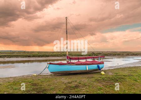 Ein Segelboot am Fluss Glaven auf den Salzwiesen im Blakeney National Nature Reserve in Blakeney, Norfolk, Großbritannien Stockfoto