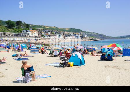 Familie am Strand mit Pop-up-Strandzelten am Sandstrand bei Lyme Regis Dorset England GB Europa Stockfoto