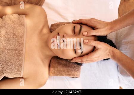 Asiatische Frau erhält Kopfmassage und genießt Entspannung im Spa. Anti-Stress-Kopfmassage Stockfoto