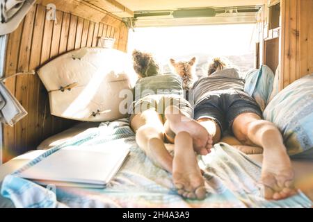 Hipster-Paar mit niedlichem Hund, der zusammen auf einem Oldtimer-Transporter reist - Life inspiration Concept mit Hippie-Leuten auf einem Minivan-Abenteuerausflug Stockfoto