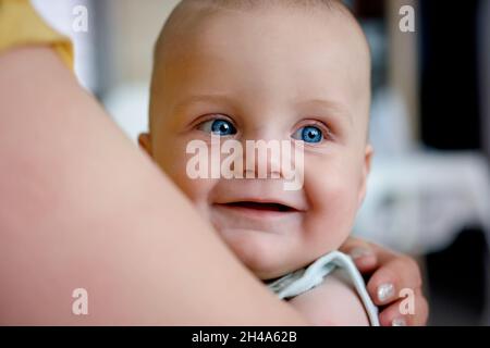 Porträt eines niedlichen lächelnden Babys mit blauen Augen, die wegschauen Stockfoto