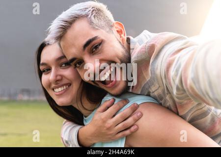 Junge, vielfältige Freunde haben Spaß beim Selfie im Freien in der Stadt - LGBT Diversity Concept - Fokus auf queeren Mann, der Make-up trägt Stockfoto