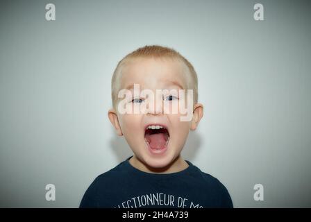 Frech kleiner Junge Blick auf die Kamera mit offenem Mund Stockfoto