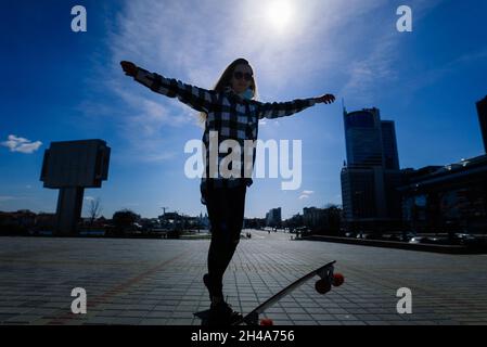 Schöne junge Skaterin Frau, die in einer Stadt auf ihrem Longboard reitet. Stockfoto