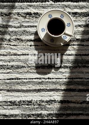 Morgen Kaffeetasse auf der geschnallten gewebten Tischdecke Stillleben mit Fensterlicht. Gemütliches Zuhause und Getränke Konzept Bild. Stockfoto