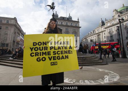 London, Großbritannien. November 2021. Tierrechtsaktivistin von People for the Ethical Treatment of Animals (PETA) hält am Weltvegantag im Piccadilly Circus in London ein Plakat, auf das Leiden und Sterben von Tieren in der Fleisch-, Ei- und Milchindustrie aufmerksam zu machen. Kredit: SOPA Images Limited/Alamy Live Nachrichten Stockfoto