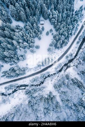 Luftaufnahme Drone Aufnahme der Kiefer und Fichten Wald bedeckt mit Schnee in der Tatra in der Slowakei mit einer ländlichen Straße. Tra Stockfoto