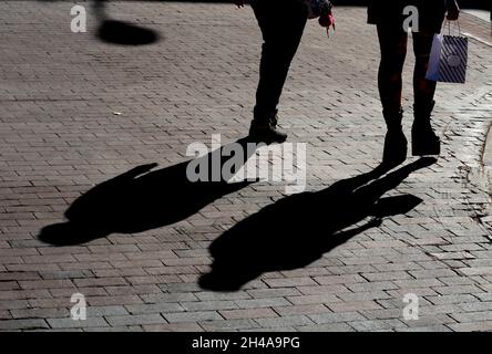 Zwei Shopper werfen lange Schatten, als sie Geschäfte in Santa Fe, New Mexico, besuchen. Stockfoto