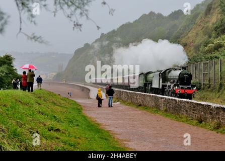 Dampfzug im Regen. Enthusiasten trotzen dem schlechten Wetter und beobachten die Mayflower-Bahntour am Sprey Point in Teignmouth, South Devon. Stockfoto