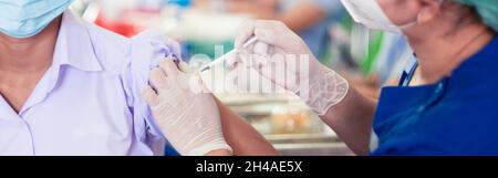 Der Arzt impft Studenten in Uniform, um Coronavirus oder Covid-19 zu verhindern Stockfoto