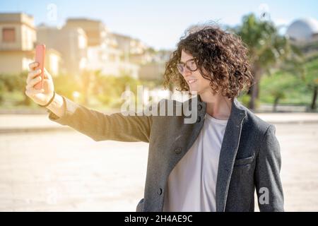 Netter junger Mann nimmt ein Selfie auf der Straße in einer städtischen Umgebung Stockfoto