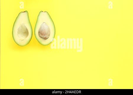 Zwei Hälften Avocado mit und ohne Samen auf gelbem Hintergrund Stockfoto