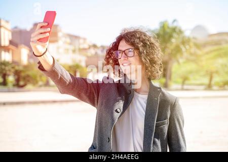 Netter junger Mann nimmt ein Selfie auf der Straße in einer städtischen Umgebung Stockfoto