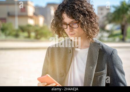 Junger Mann, der mit dem Smartphone auf der Straße chattet Stockfoto
