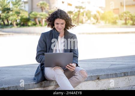 Der junge Mann arbeitet auf der Straße am Laptop Stockfoto