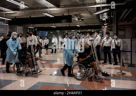 Samut Prakan, Thailand. November 2021. Thailand U-23 verletzte Fußballspieler werden bei ihrer Rückkehr von einem Fußballspiel in der Mongolei am Flughafen Suvarnabhumi weggerollt.Thailand öffnet das Land am 1. November für vollständig geimpfte Reisende aus Ländern mit geringem Risiko für eine Coronavirus-Pandemie, ohne Quarantänepflicht zu durchlaufen. Dies soll die Tourismusindustrie und die Wirtschaft ankurbeln. Kredit: SOPA Images Limited/Alamy Live Nachrichten Stockfoto