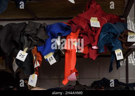 Rollen aus mehrfarbigem Geniune-Leder im Regal im Werk. Buntes Leder mit Zahlen für die Herstellung von handgefertigten Schuhen und Taschen Stockfoto