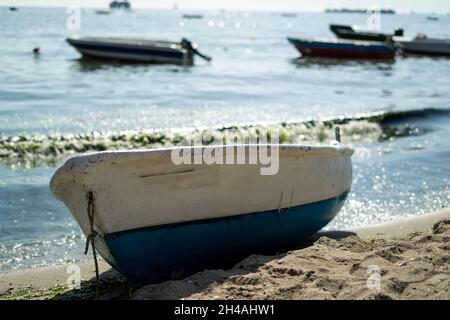 Einzelboot auf Sand mit Meer zwischen Zirkelfäkne und Blick auf den Strand mit anderen Booten im Hintergrund Stockfoto
