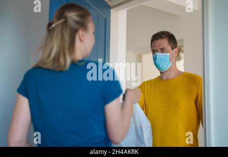 Maskierter Mann liefert während einer Pandemie Nahrung. Stockfoto