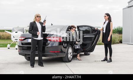 Professionelle bewaffnete Team von weiblichen und männlichen Bodyguards schützen Prominenten Person in der Auto-Limousine. Sicherheitsschutz für Bodyguard und VIP-Personen. Bekennen Stockfoto